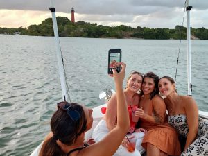 Taking a selfie with friends on a boat with the Jupiter Lighthouse in the background during a 3 hour sightseeing tour