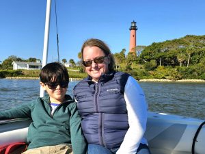 Mom and son enjoying a boat ride in Jupiter Florida with a lighthouse in the distance
