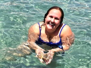 Woman holding a brown, juvenile sea star in the water at peanut island
