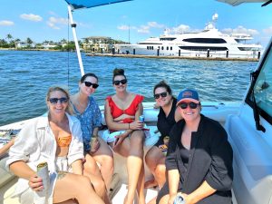 5 friends on a narrated sightseeing boat tour in West Palm Beach with a yacht in the background