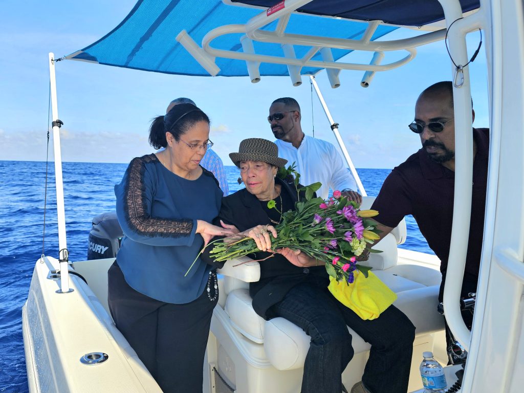 A family of six spreading flowers on the ocean during an ash scattering release