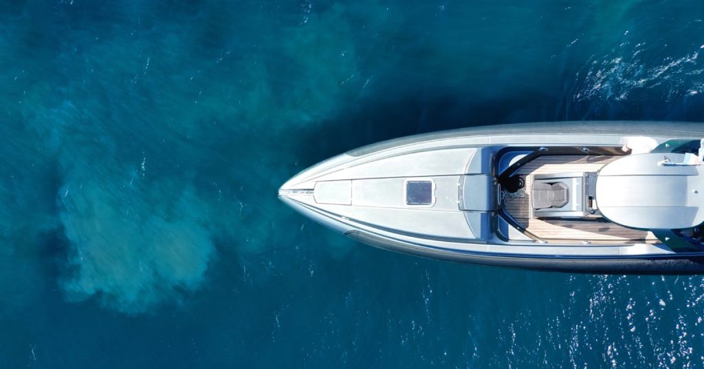 An aerial drone view of a luxury speedboat cruising at high speed in the deep blue sea. The deck is empty.