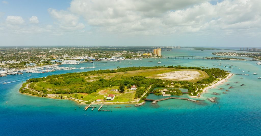 An overview of Peanut Island, Florida, in West Palm Beach. The water is clear and cerulean, and the sky is partly cloudy.